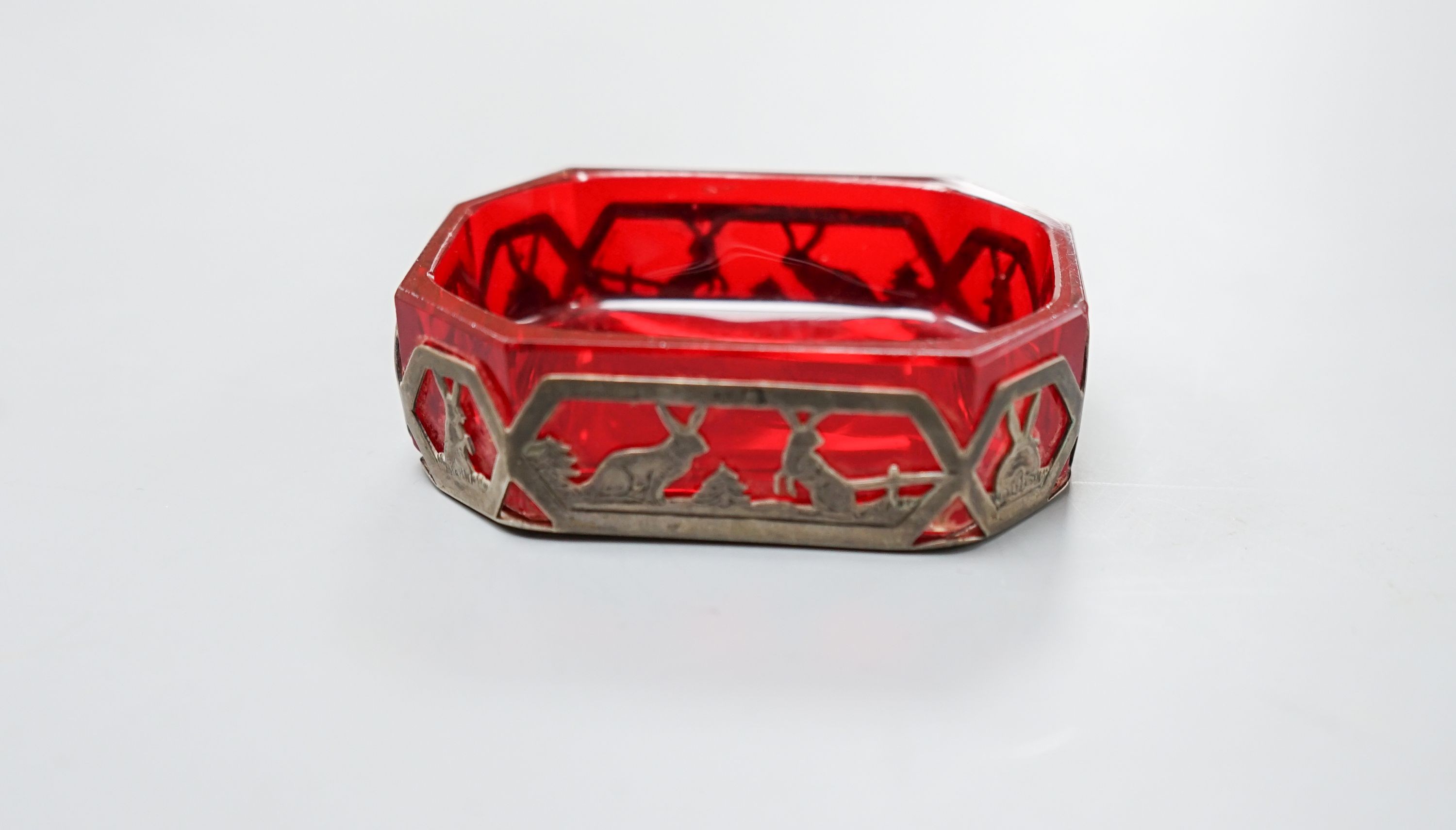 An early 20th century Austro Hungarian gilt white metal snuff box, 82mm and a similar later mounted ruby glass dish, 72mm.